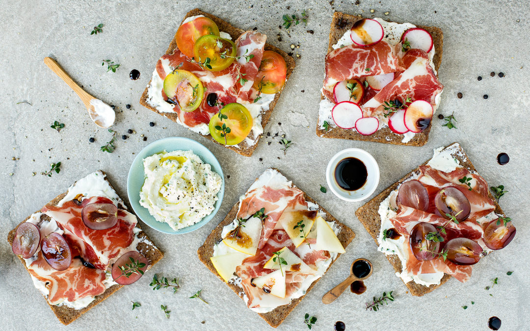 Crostini di pane nero con caprino aromatizzato, frutta, verdura e Coppa di Parma IGP